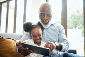 grandpa and girl with tablet sitting on couch