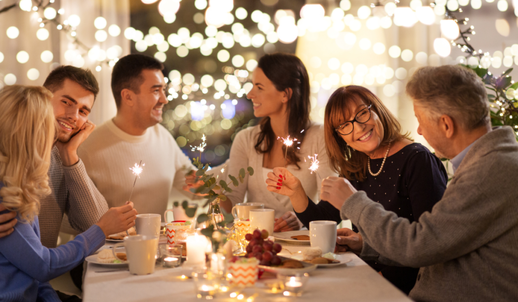 family eating dinner at table with twinkly lights holding sparklers