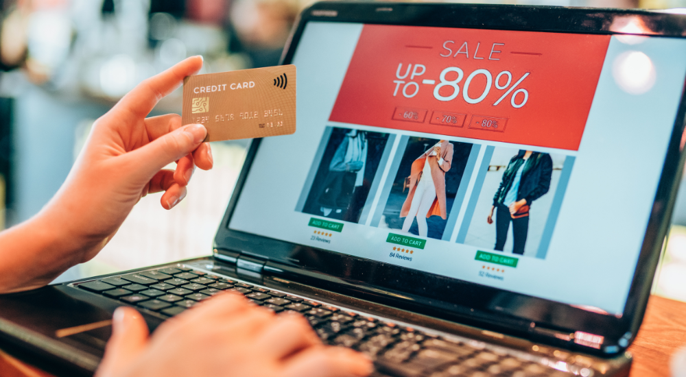 person holding credit card while shopping online with a laptop