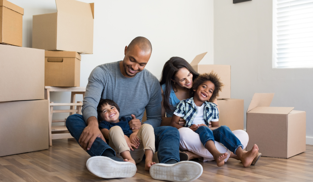 FAMILY SITTING ON FLOOR OF NEW HOUSE WITH BOXES